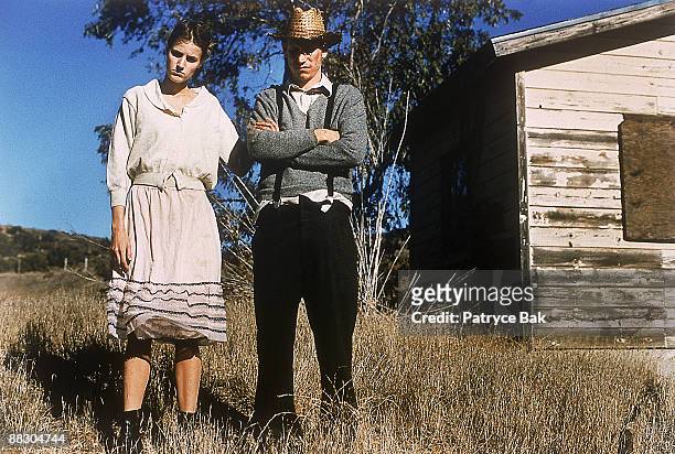 couple standing in field by shack - amish man stock-fotos und bilder