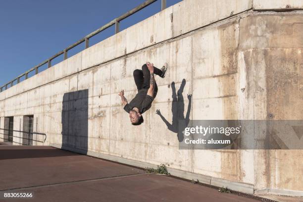 uomo che fa il capovolgimento mentre pratica il parkour in città - fare le capriole all'indietro foto e immagini stock