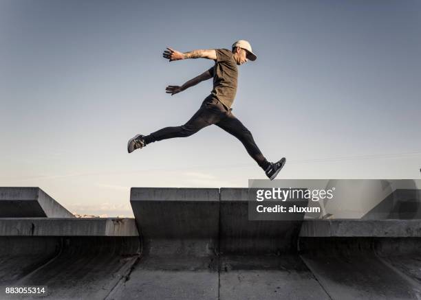 hombre practicar parkour en la ciudad - acrobatic activity fotografías e imágenes de stock