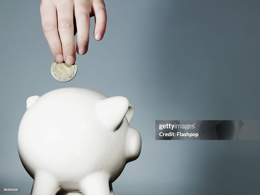 Hand putting coin in piggy bank