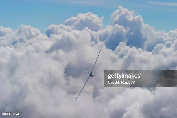 a glider flying straight towards camera above the clouds. - gleiten stock-fotos und bilder