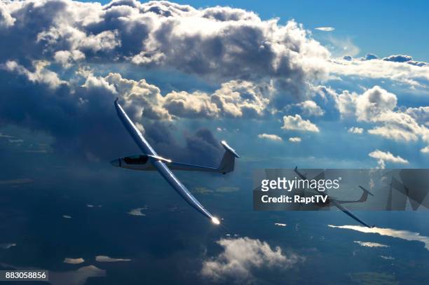 two motor gliders flying up through a dramatic cloudscape. - gleiten stock-fotos und bilder