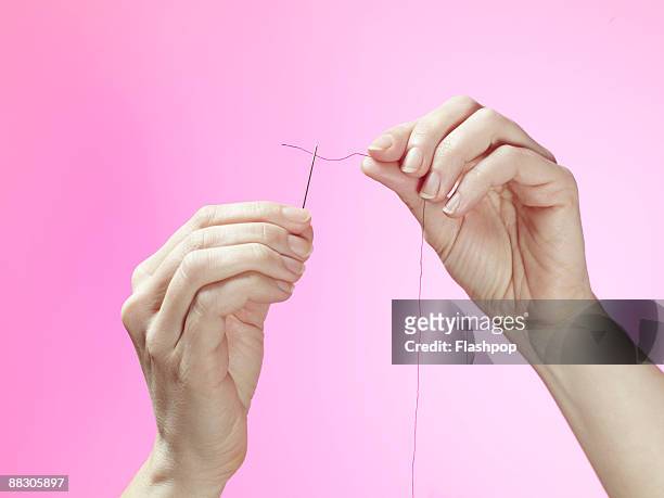 hands threading sewing needle - nadel kurzwaren stock-fotos und bilder