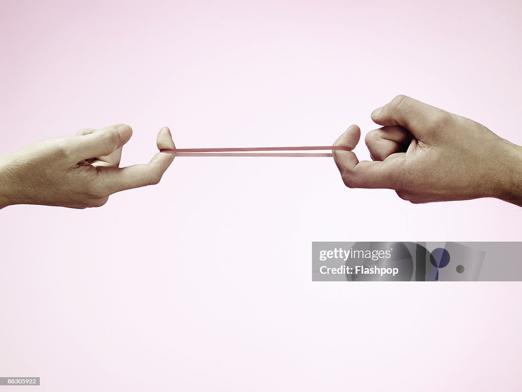 Hands pulling rubber band