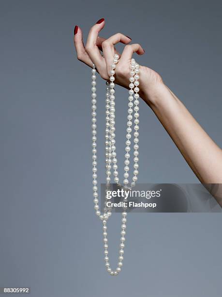 hand holding pearl necklace - pearl necklace stock pictures, royalty-free photos & images
