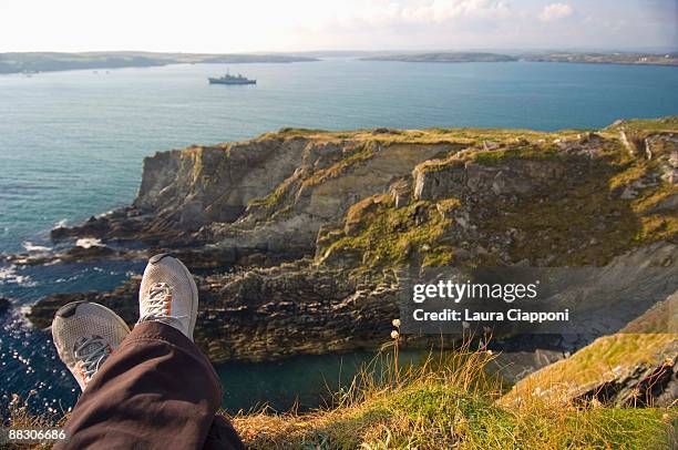 person sitting on cliff overlooking ocean - pov shoes ストックフォトと画像