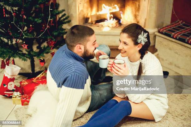 loving couple near fireplace in christmas decorated house interior - face surprise heat stock pictures, royalty-free photos & images