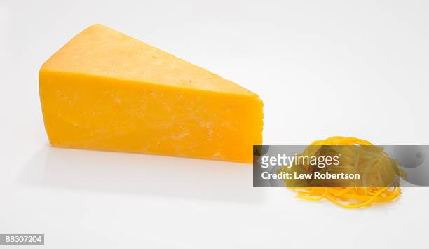 wedge and shredded cheddar cheese on white - cheddar kaas stockfoto's en -beelden
