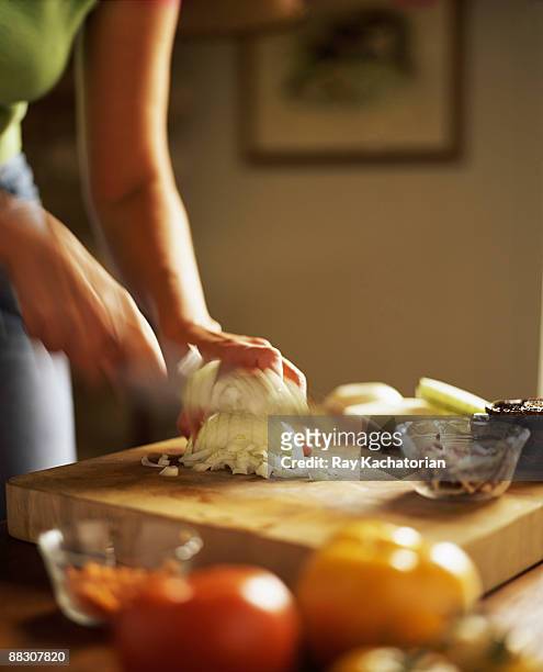 woman chopping onion on wooden cutting board - coupant photos et images de collection