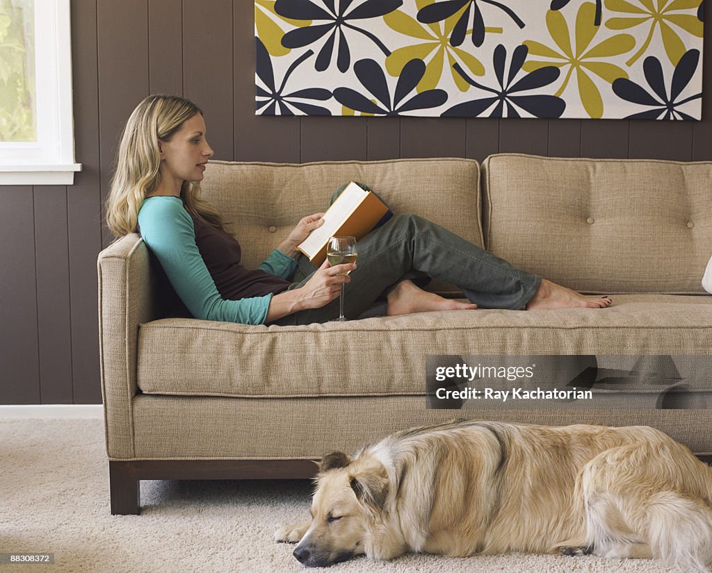 Woman relaxing with book and glass of wine in contemporary living room