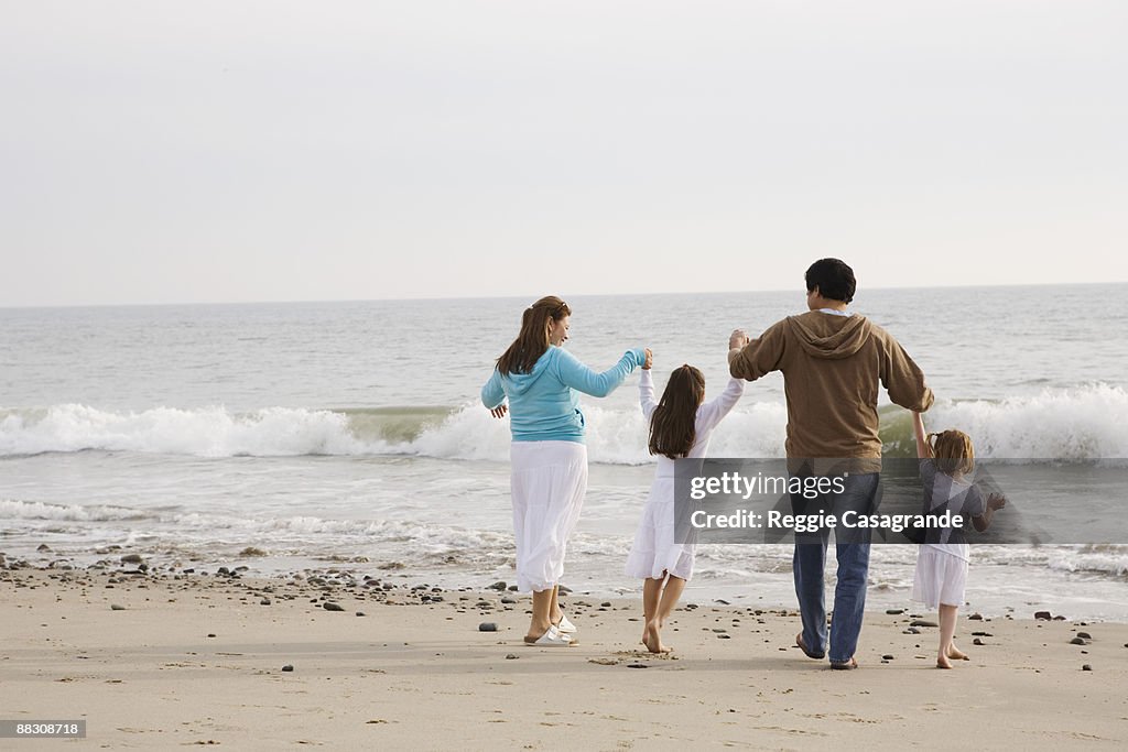 Family holding hands on beach, Malibu, California
