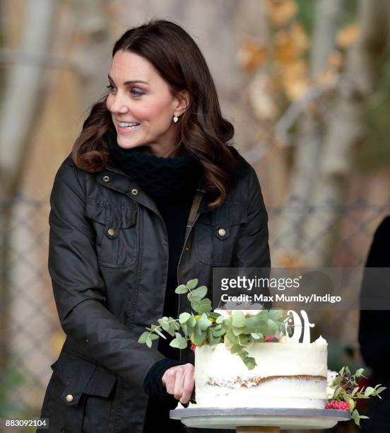 Catherine, Duchess of Cambridge cuts a cake as she visits the Robin Hood Primary School to celebrate ten years of The Royal Horticultural Society...