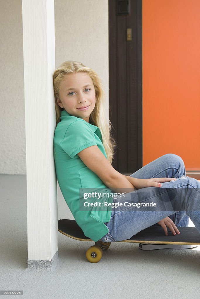 Pre-teen girl sitting on skateboard