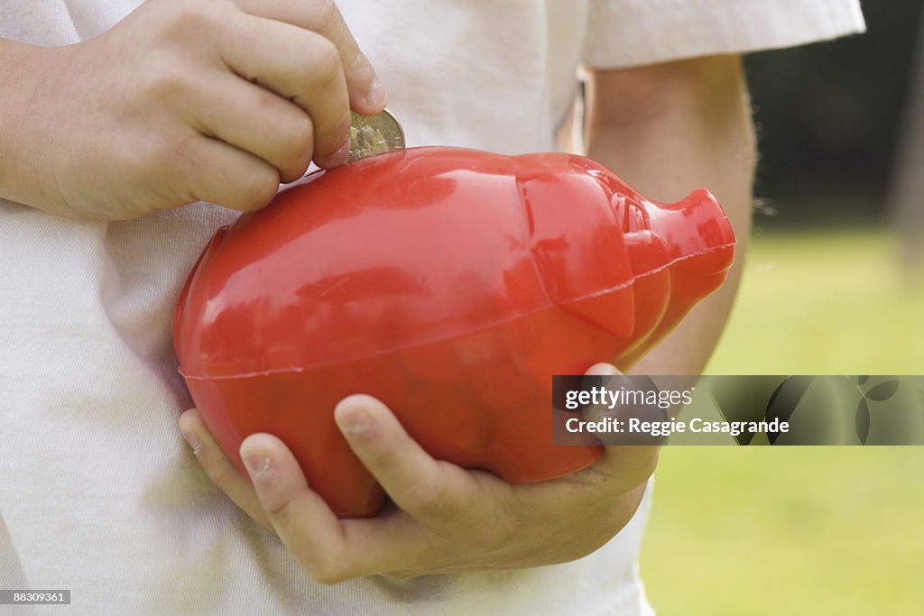 Child putting money in piggy bank