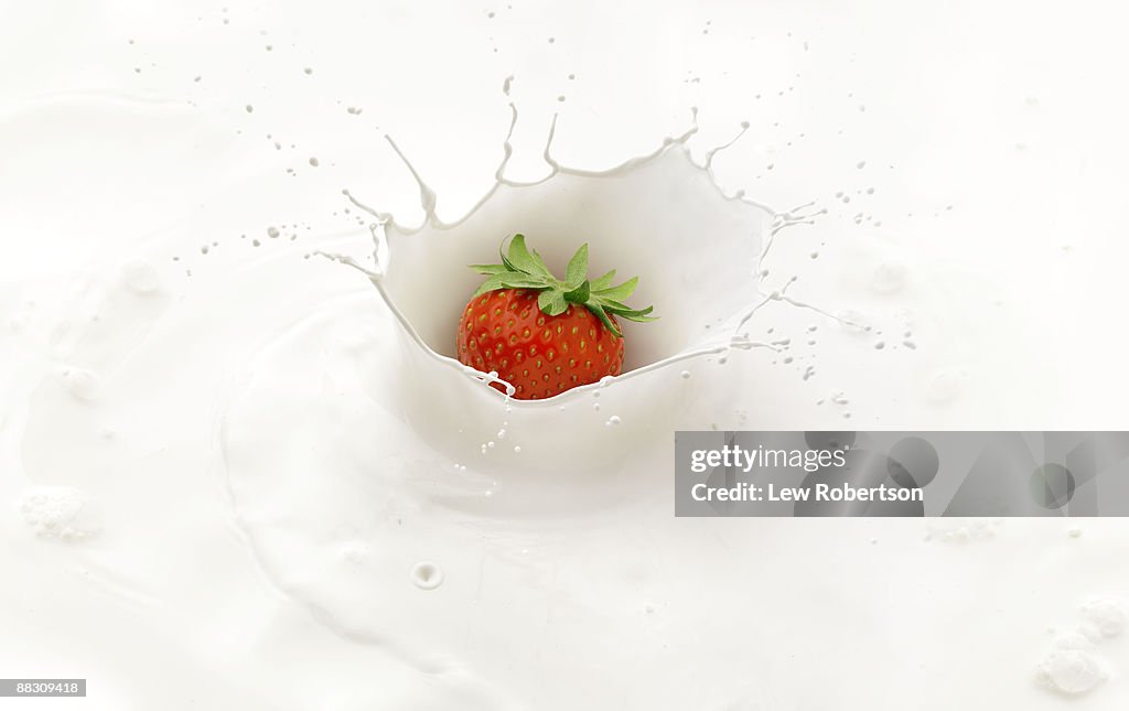 Strawberry splashing into cream