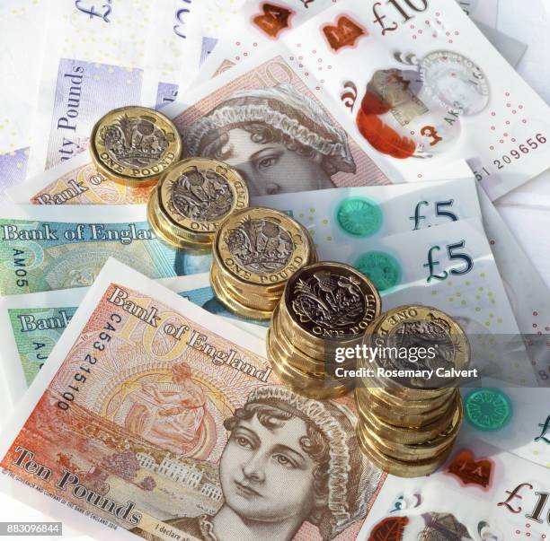 one pound coins in ordered stacks on pound notes. - british pound note stock pictures, royalty-free photos & images