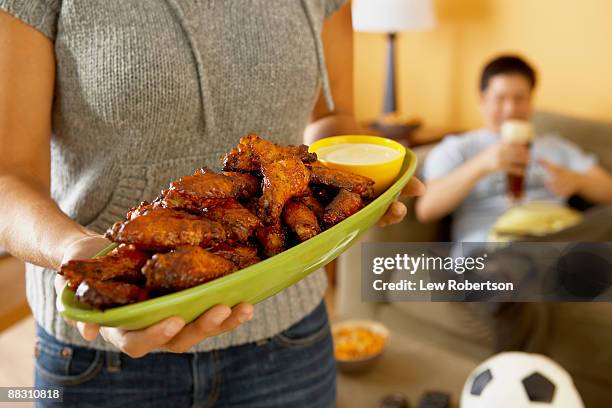 woman holding platter of buffalo wings - chicken wing stock-fotos und bilder