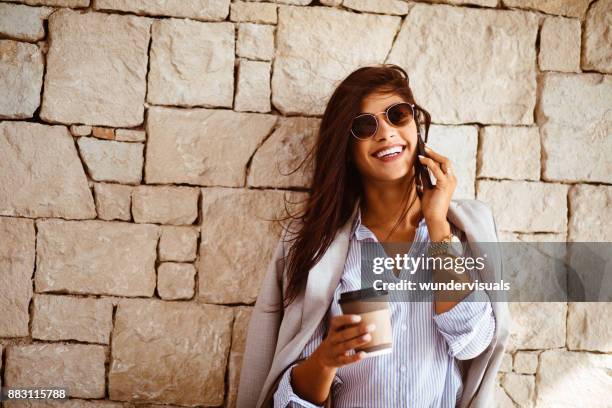 donna bruna felice che beve caffè e parla al telefono - blazer foto e immagini stock