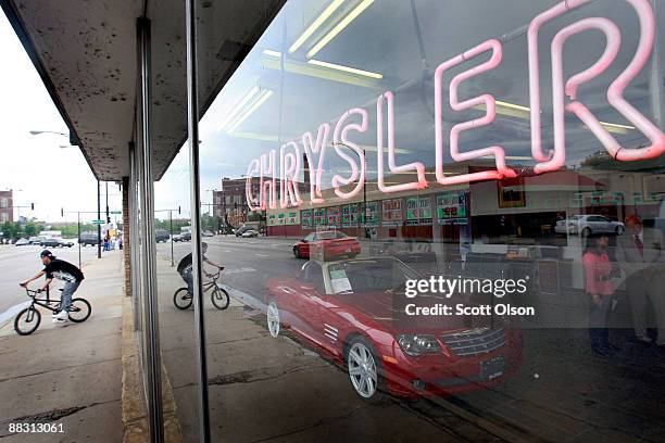 Neon sign shines out the showroom window of Balzekas Chrysler dealership June 8, 2009 in Chicago, Illinois. The dealership, which has been in...