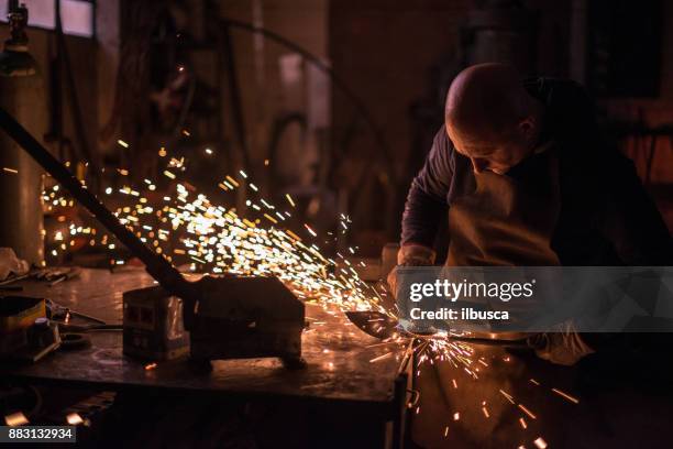 artista fabbro che lavora nel suo studio di fucina creando un albero di cancello - fabbro ferraio foto e immagini stock
