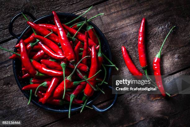 rote chilischoten auf rustikalen holztisch von oben gedreht. - bowl of chili stock-fotos und bilder