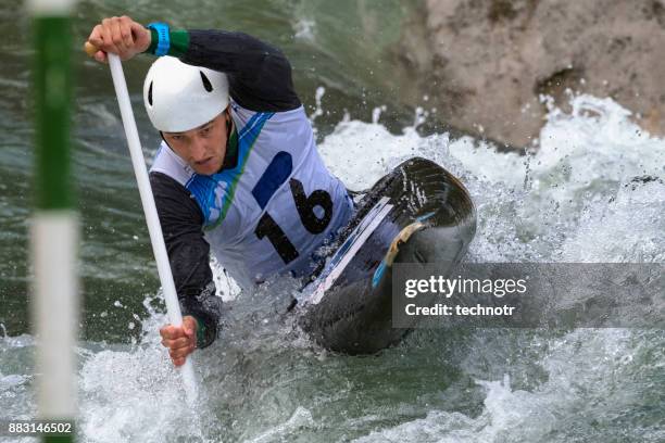 front view of young male canoeist in the whitewater reaching the green gate - swift river stock pictures, royalty-free photos & images