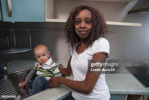 nanny taking care of playful boy in a kitchen sink - nanny smiling stockfoto's en -beelden