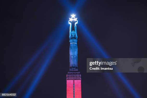 freedom monument of latvia in the nighttime amidst the festival “staro riga” - in two colors - riga stock pictures, royalty-free photos & images