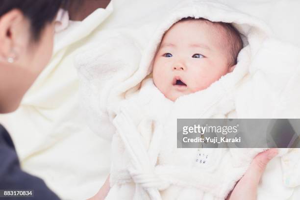pasgeboren baby in een pluizige witte badjas tikte omhoog door moeder - bath robe stockfoto's en -beelden