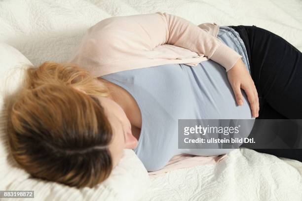 Schwangere Frau liegt auf Bett