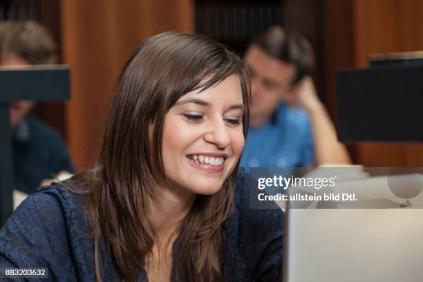 Studentin schaut erfreut beim Lernen in Bibliothek