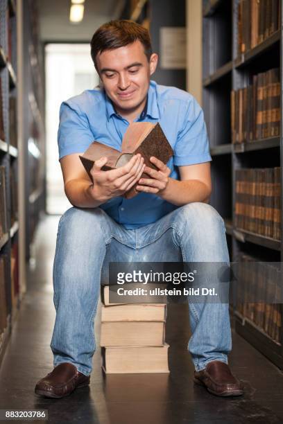 Student lernt auf Bücherstapel in der Bibliothek