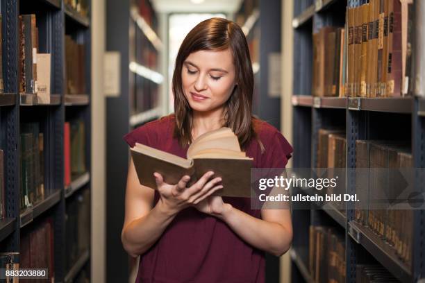 Studentin liest in Buch in Bibliothek