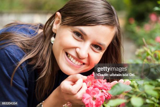 Frau mit Blume lächelt in die Kamera