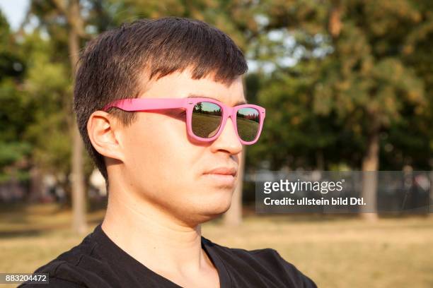Junger Mann mit pinker Sonnenbrille