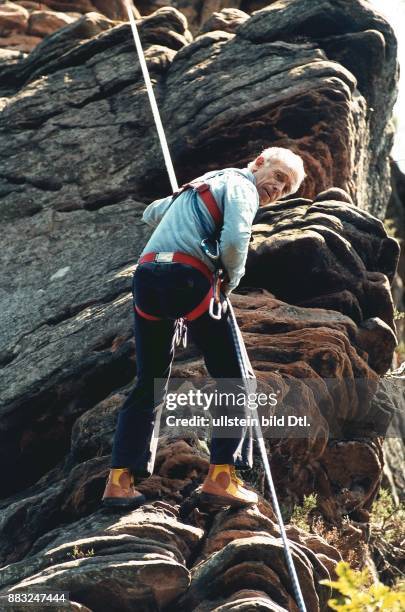 Heiner Geißler, Politiker der CDU, beim Bergsteigen. Er seilt sich vom Felsen ab, trägt gelbe Sportschuhe. .