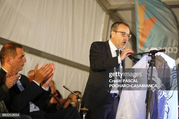 Pe a Corsica nationalist party candidate for Corsican regional elections Gilles Simeoni applauds as candidate Jean-Guy Talamoni delivers a speech...