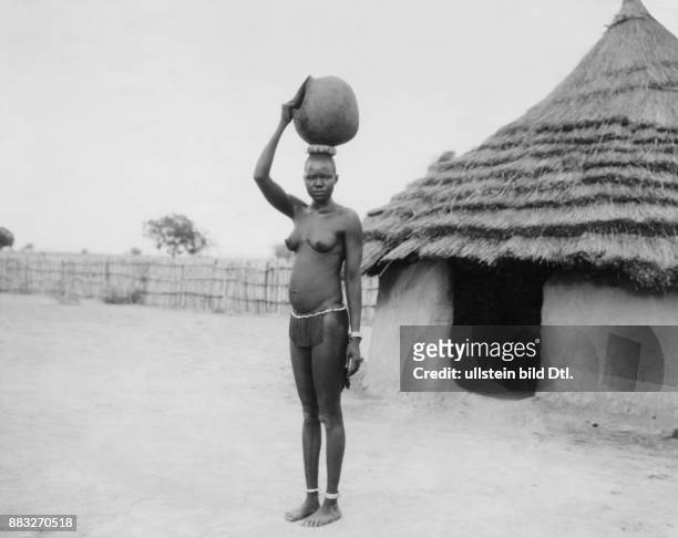 Sudan, Niltal, Hausa (auch junge Frau mit einem Wasserkrug auf dem Kopf vor einer traditionellen Hütte Aufnahme: Ewing Galloway Originalaufnahme im...