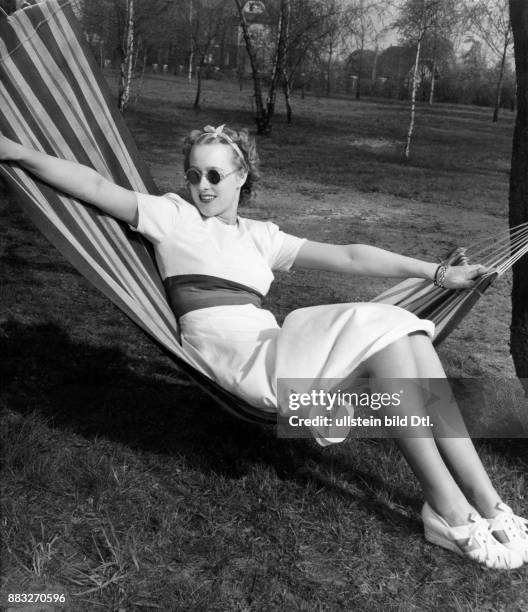 Ein Model in einer Hängematte liegend präsentiert ein Sommerkleid Aufnahme: Sonja Georgi Originalaufnahme im Archiv von ullstein bild