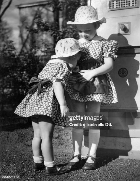 Geschwister, zwei kleine Schwester tragen das gleiche Kleid, ein weiss-blau gemustertes Dirndl mit blauer Schürze , die größere schwester hat Süsses...