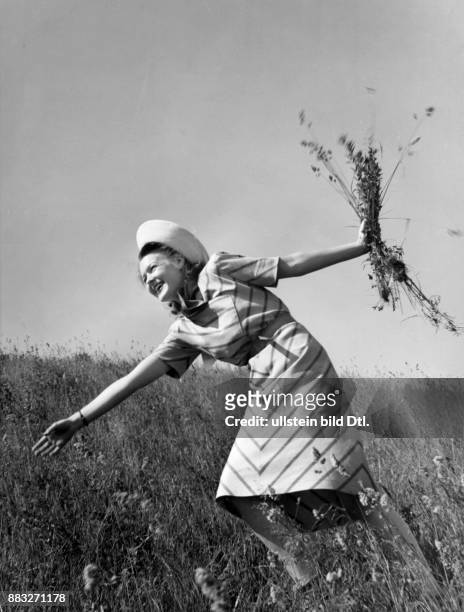 Ein Model präsentiert ein gestreiftes Sommerkleid beim Blumenpflücken auf einer Wiese Aufnahme: Sonja Georgi Originalaufnahme im Archiv von ullstein...