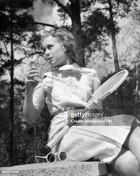 Ein Model mit einem Tennisschläger präsentiert ein Sommerkleid Aufnahme: Sonja Georgi Originalaufnahme im Archiv von ullstein bild