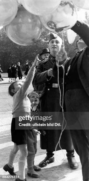 Kleine Kinder verlangen nach Luftballons von einem Soldaten auf einer Straße Aufnahme: Hanns Hubmann Originalaufnahme im Archiv von ullstein bild