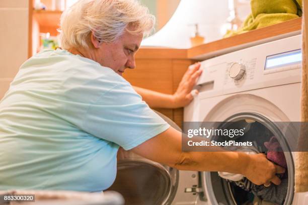 ältere frauen, die wäsche aus der waschmaschine - homemaker stock-fotos und bilder