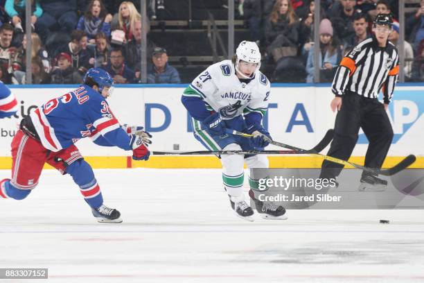 Ben Hutton of the Vancouver Canucks skates with the puck against Mats Zuccarello of the New York Rangers at Madison Square Garden on November 26,...