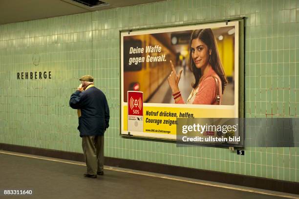 Bahnlinie U6, U-Bahnhof Rehberge, Plakat der BVG mit dem Text: Deine Waffe gegen Gewalt. Notruf druecken, helfen Courage zeigen, Davor steht ein Mann...