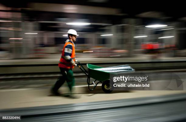 Deutschland Brandenburg Schoenefeld - Bauarbeiter mit einer Schubkarre auf der Baustelle fuer den Bahnhof Grossflughafen...