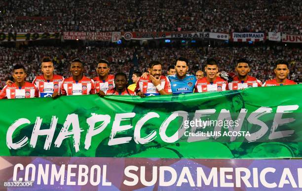 Players of Colombian team Junior pose for pictures behind a banner with the name of Brazilian club Chapecoense, before the start of their Copa...