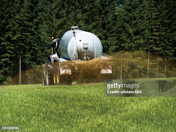 Ein Bauer fährt mit Gülle auf einem Feld zum Düngen