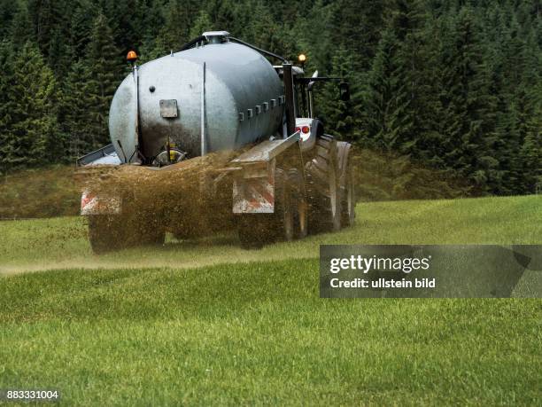 Ein Bauer fährt mit Gülle auf einem Feld zum Düngen